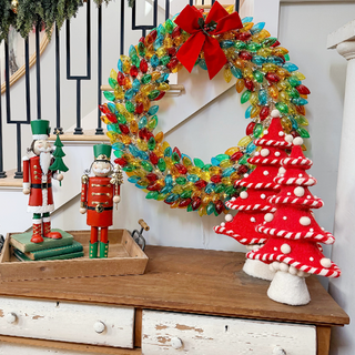 Woman holding set of two metal nutcracker decorations showing size comparison - medium 16 inch and large 16.5 inch nutcrackers with distressed finish