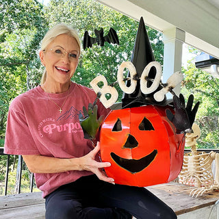 Woman holding large metal jack-o'-lantern pumpkin decoration