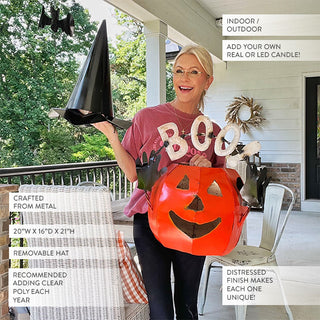 Woman showing removable witch hat from metal pumpkin jack-o'-lantern Halloween decoration