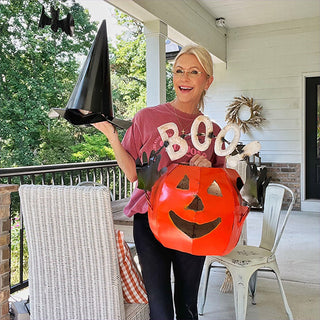 Woman holding large metal pumpkin jack-o'-lantern