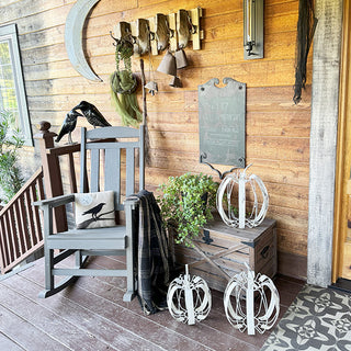 Farmhouse porch decorated with rustic metal pumpkin accents, rocking chair, and fall-themed decor