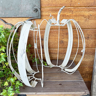 Close-up of distressed white metal pumpkin decor showing side opening feature for storage or display