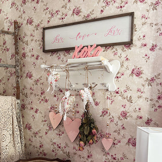 Distressed white ornate wall shelf with hooks displaying Valentine's Day hearts and dried roses