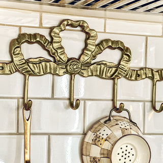 Brass farmhouse wall hooks holding kitchen utensils