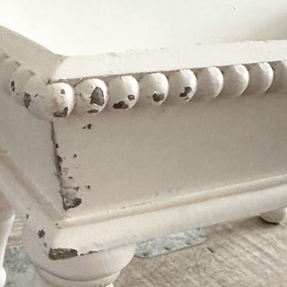 Turned wood leg detail on distressed white riser