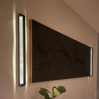 Modern black sconces lighting large wall art.