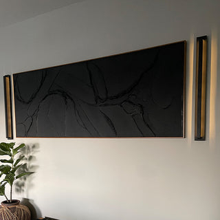 Pair of black sconces flanking large wall art.