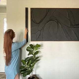 Woman mounting black modern wall sconce.