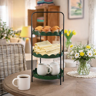 Vibrant green 3-tier scalloped metal server stand with black frame holding muffins linens and teapot on dining table