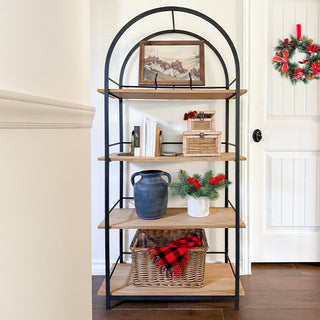 Arched black metal and natural wood bookshelf styled with home décor accents including books, vases, wicker basket, and framed art