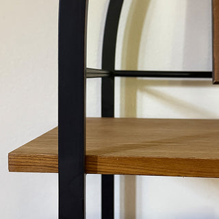 Close-up of arched black iron frame and natural wood shelf detail showing craftsmanship and smooth finish