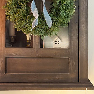 Glass door wall cabinet with wreath and decor