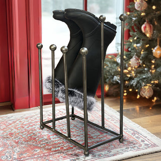 Distressed black iron boot holder rack in holiday entryway with Christmas tree and red curtains
