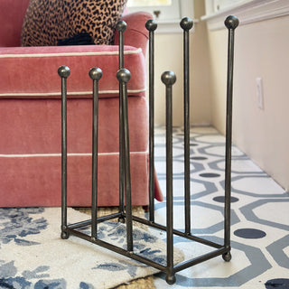 Full view of 7-pole distressed iron boot organizer rack on patterned rug