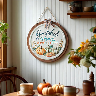 Round farmhouse wall sign with pumpkins and text 'Grateful Hearts Gather Here' hanging in cozy dining room
