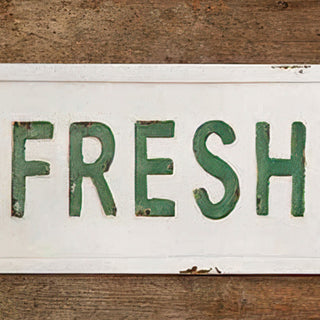 Detail shot of embossed FRESH lettering on vintage farmhouse metal sign showing distressed finish