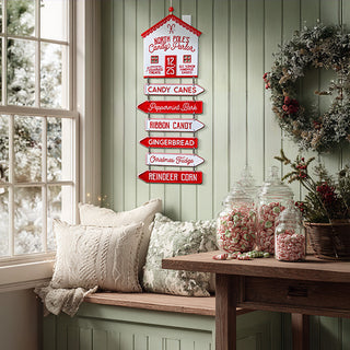 Red and white metal Christmas wall sign with jute hanger displaying candy shop directions in farmhouse style living room with window seat