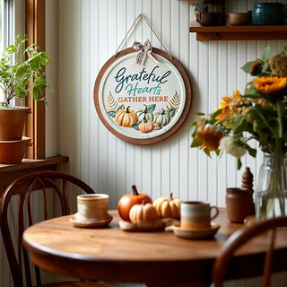 Farmhouse dining nook with seasonal wall sign 'Grateful Hearts Gather Here' styled with pumpkins and coffee mugs
