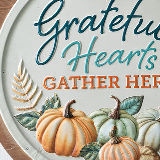 Detailed view of embossed pumpkins and lettering on 'Grateful Hearts Gather Here' rustic fall wall sign.