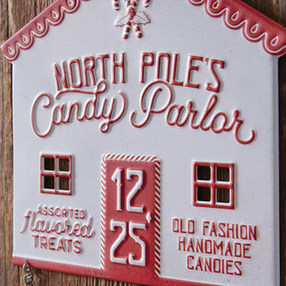 Close up detail of North Pole Candy Parlor sign showing dimensional raised lettering candy cane door and decorative scalloped trim