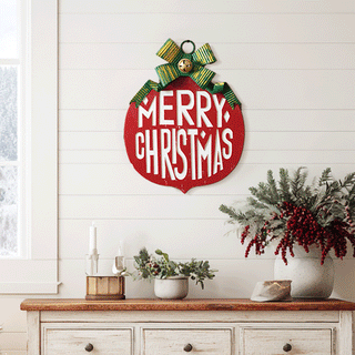 Red Merry Christmas ornament wall sign with green striped bow on white shiplap wall above farmhouse console table