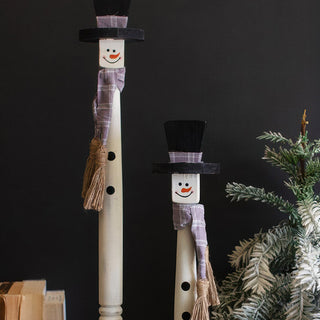 Close-up detail of wooden snowman face with hand-painted features plaid scarf and black button accents