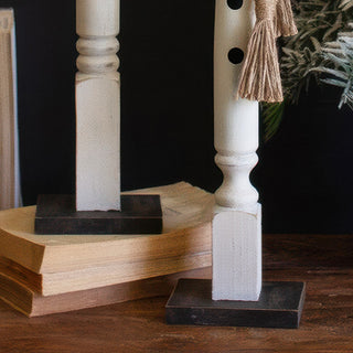 Turned wooden spindle base construction detail showing distressed white farmhouse finish and stability