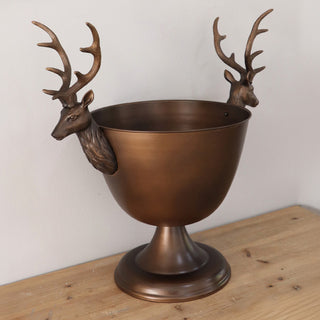 Bronze stag pedestal bowl filled with assorted wine bottles, used as a holiday beverage chiller on wooden tabletop