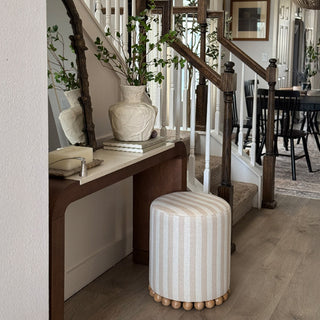 Striped upholstered ottoman styled in modern entryway