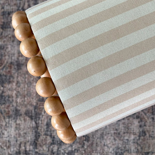 Striped ottoman with natural wood ball base detail