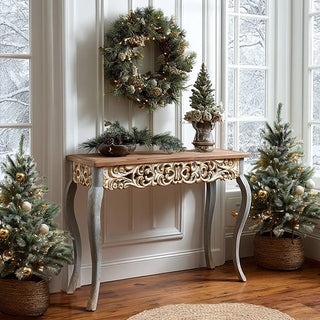 French country console table with ornate carved apron displayed in elegant holiday entryway with Christmas wreath and greenery
