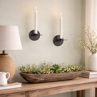 Decorative setup with a wooden bowl, lamp, and taper candle holders on a neutral wall.
