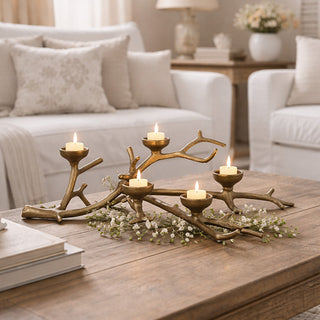 Cast iron branch tealight holder with five lit candles on coffee table in elegant white living room with sofa
