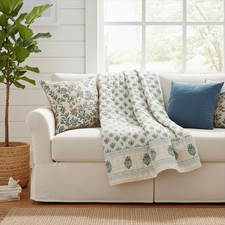 Lifestyle shot of block print throw on white couch with coordinating decorative pillows in bright room