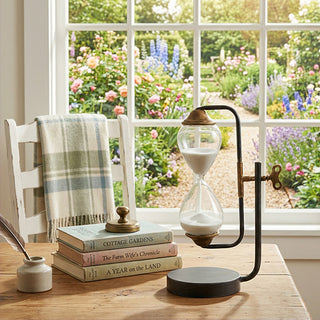 Hourglass timer on black metal stand styled with books near sunny window