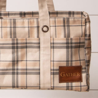 Detail shot of embossed brown leather Gather tag on neutral plaid cotton tote