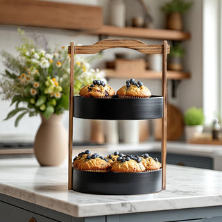 Modern farmhouse two tier serving tray with natural wood handle and black metal trays displaying muffins on white marble kitchen counter