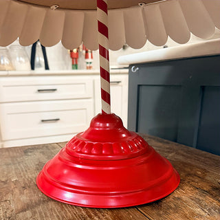 Close-up of glossy red metal base and striped pole of three-tier serving tray on wooden countertop