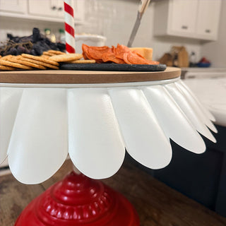 Detail of scalloped white metal tray edge holding crackers, cheese, and charcuterie on festive serving stand