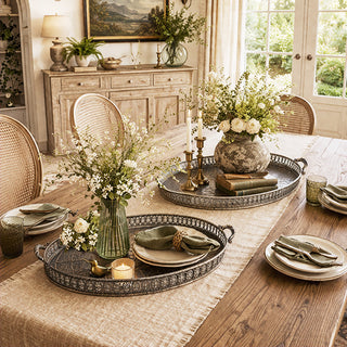 Set of two antique bronze metal serving trays with embossed botanical details on farmhouse dining table