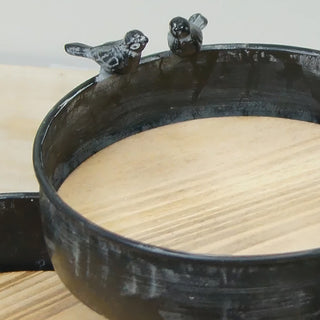 Close-up detail of bird accent on rustic black metal tray rim
