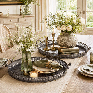 Close-up of embossed metal tray showing intricate botanical pattern and antiqued bronze finish detail