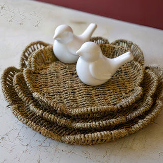Stacked scalloped seagrass trays with white ceramic bird decorations