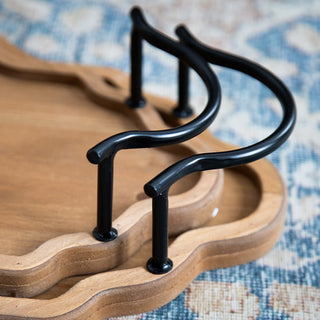  Detail view of decorative curved iron handles on scalloped wood serving tray