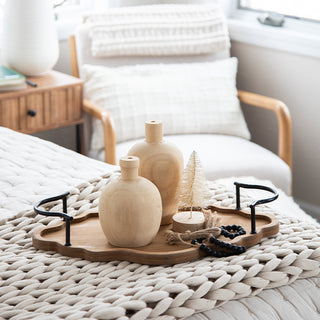 Cozy bedroom styling with scalloped wood tray holding candles and wooden vase decorations