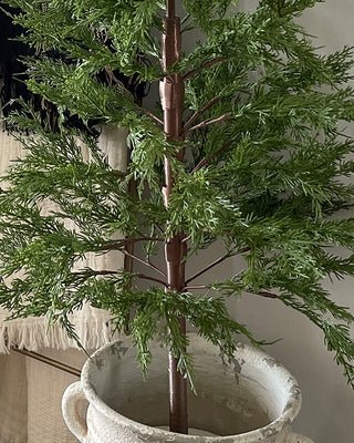 Five foot potted Christmas tree styled beside fireplace