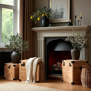 Stacked set of three carved wooden storage trunks with geometric panel detailing and metal hardware, styled in an elegant vintage living room for home décor and organization