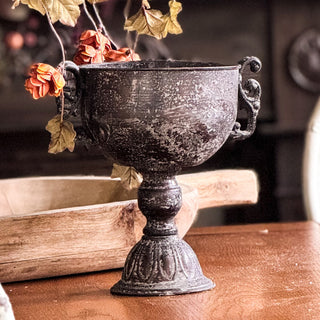 Decorative black urn with dried flowers on a wooden surface