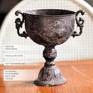 Decorative black urn with dried flowers on a wooden surface