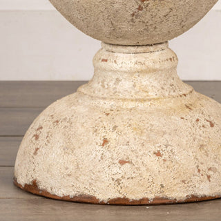 Close-up detail of distressed cream metal urn pedestal base showing heavily textured rustic finish with cream ivory and russet tones